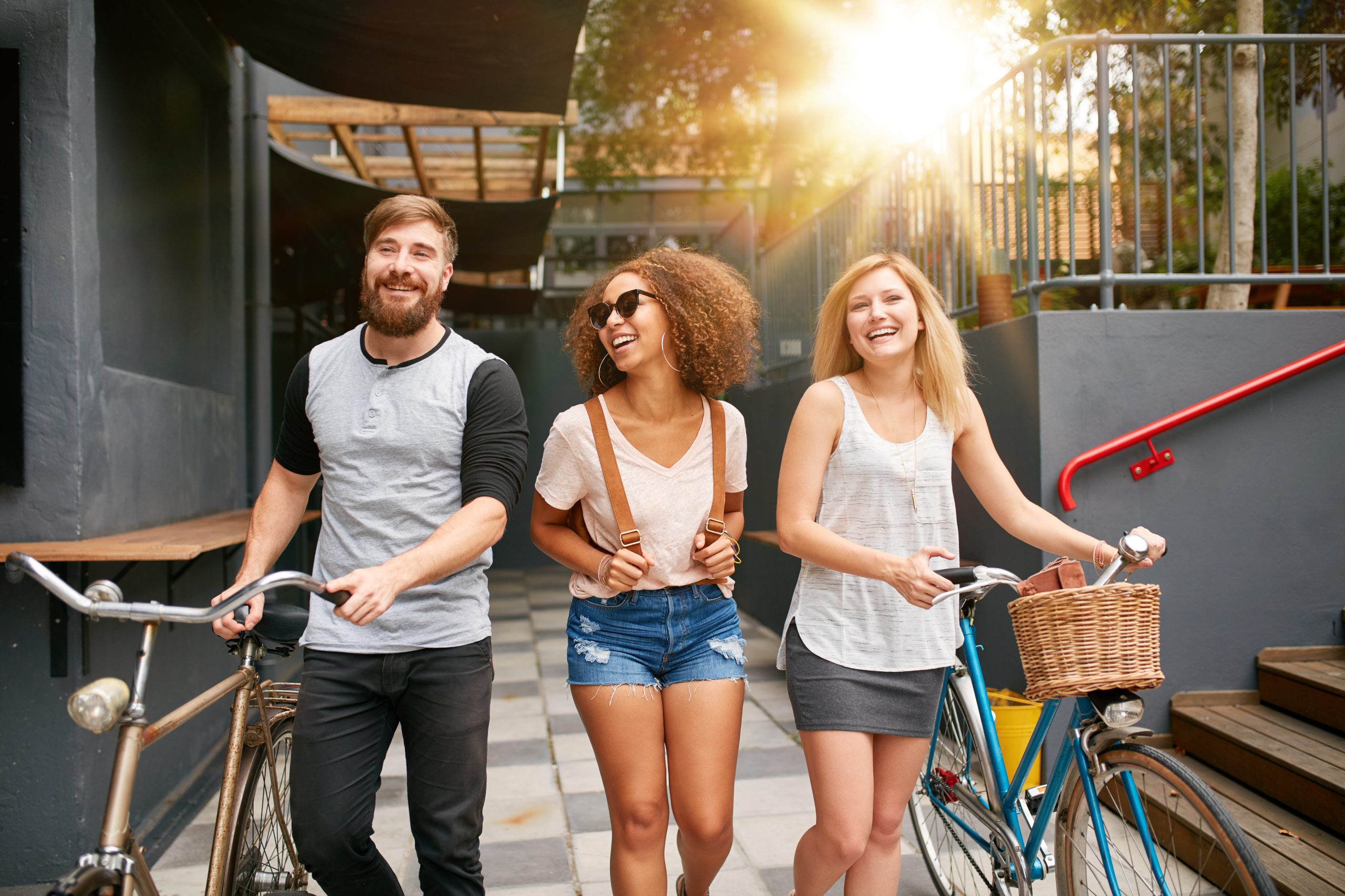 Three young adults walking together with bike
