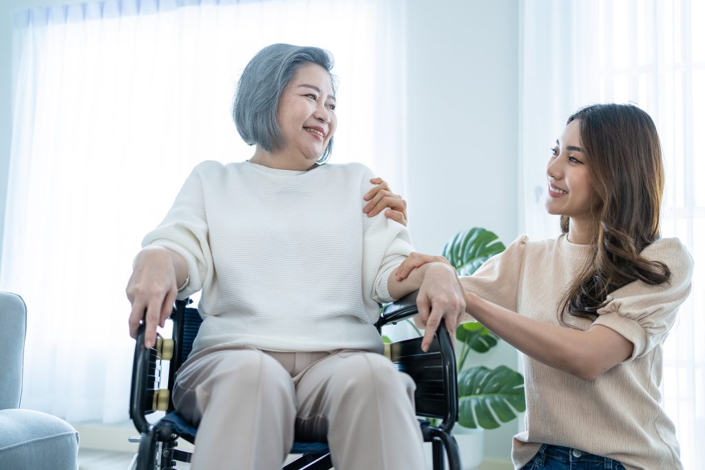 Young Asian Woman supporting handicapped mother